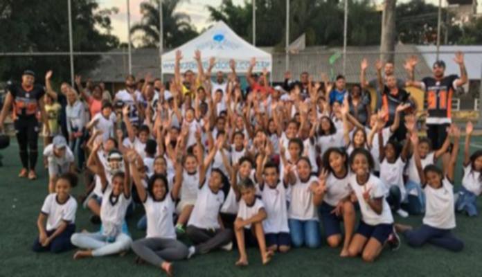 crianças sentadas no gramado comemoram junto aos atletas com os braços erguidos