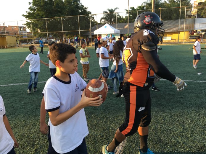 com orientação do atleta crianças lançam a bola americana 