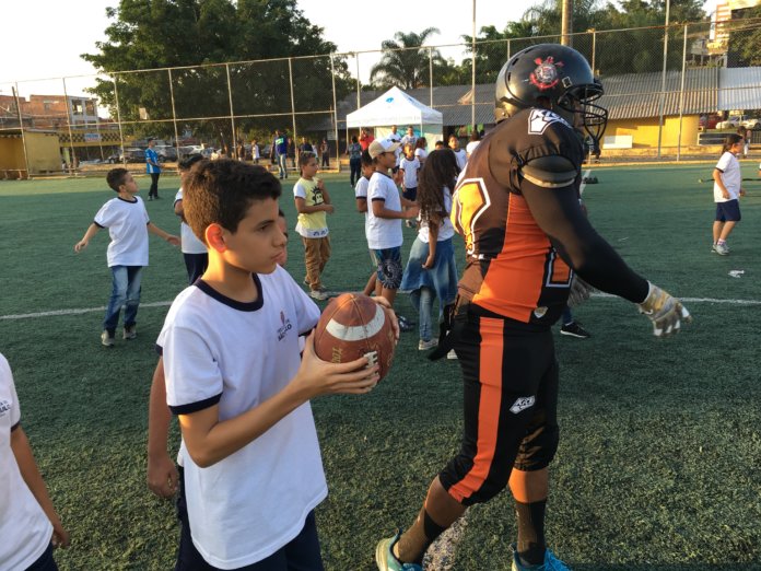 com orientação do atleta crianças lançam a bola americana 