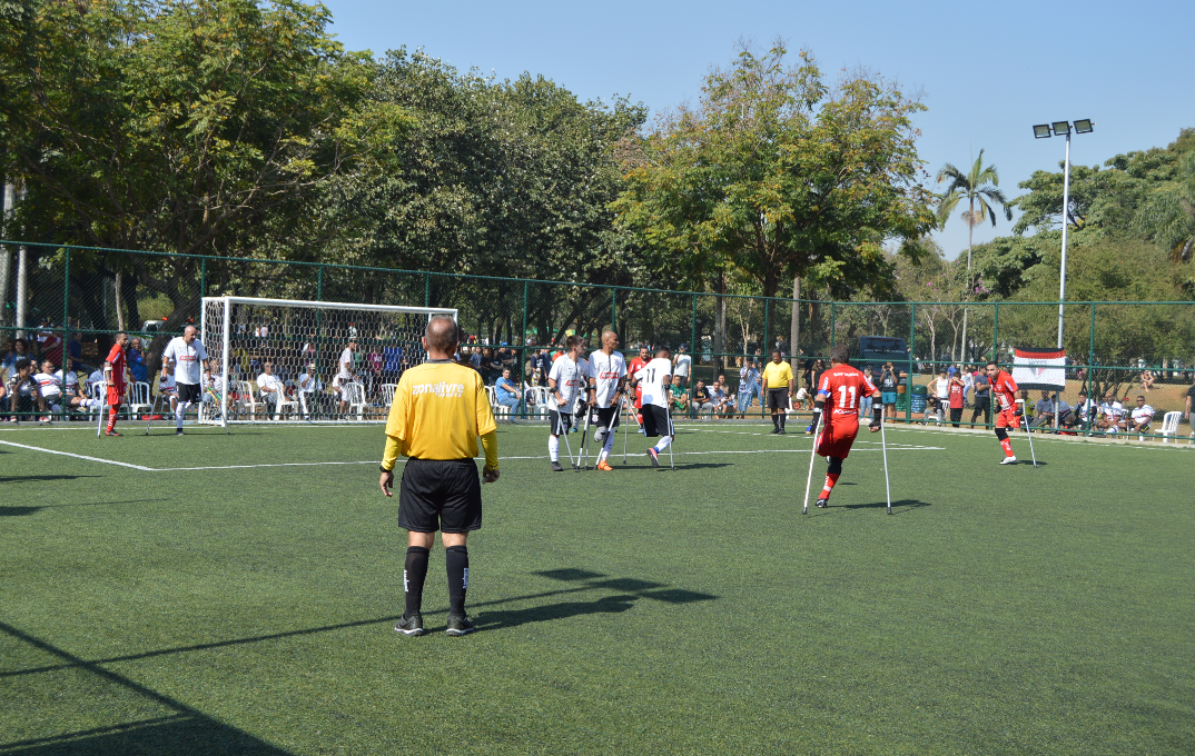 Jogadores amputados durante partida em campo de futebol aberto.