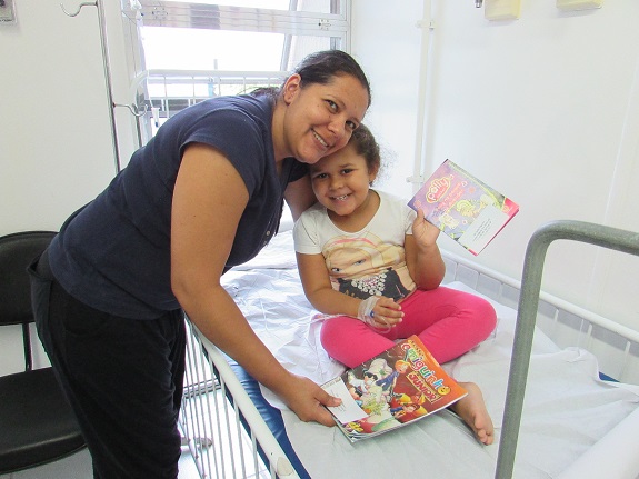 Mãe e filha na sala de pediatria mostram livros infantis
