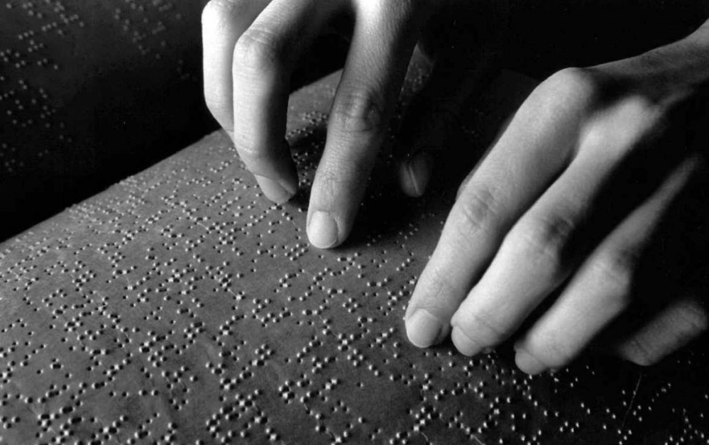 mãos tocando uma livro em Braille