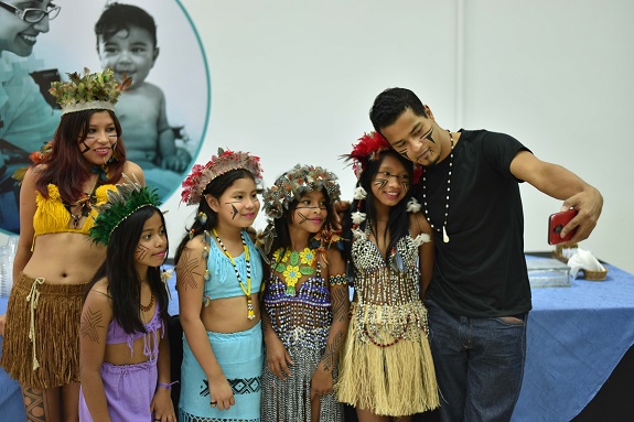 Meninas posam com trajes típicos ao lado do líder da aldeia