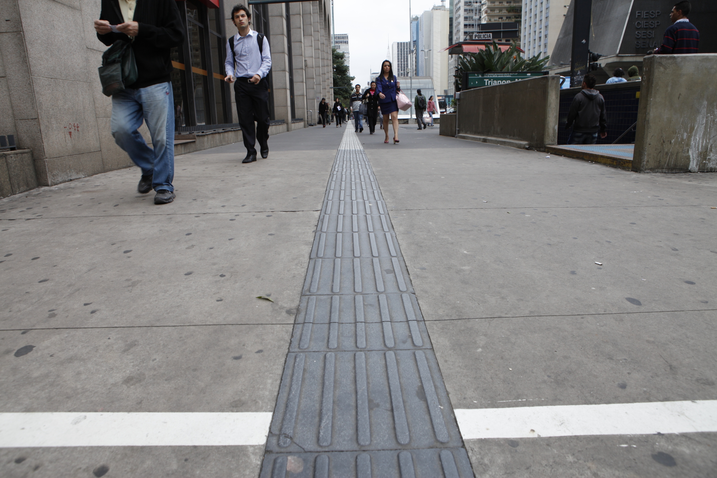 Foto de calçada de concreto com faixa de piso tátil 