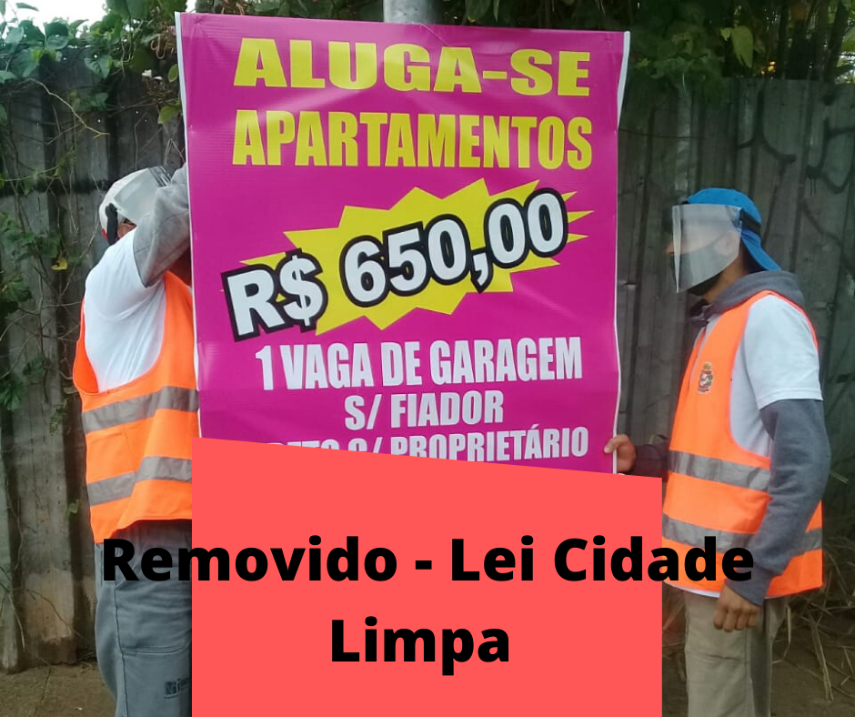 Dois homens carregam placa de anúncio irregular de aluguel de apartamentos. Texto montado informa que foi removido pela Lei Cidade Limpa. 