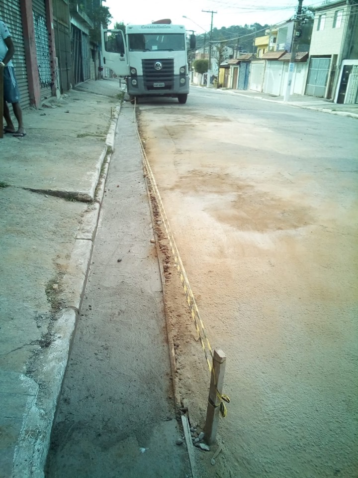 Reconstrução de sarjeta na rua Doutor Paulo de Queiroz, Jardim Nove de Julho. O cimento ainda apresenta sinais de umidade. Ao fundo, um caminhão está parado.