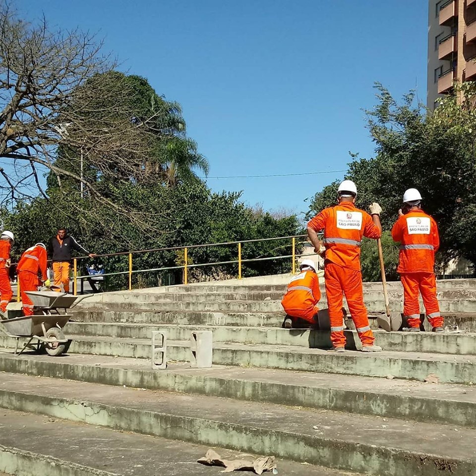 Funcionários trabalhando na escadaria da praça Cataguarino, sob sol forte.