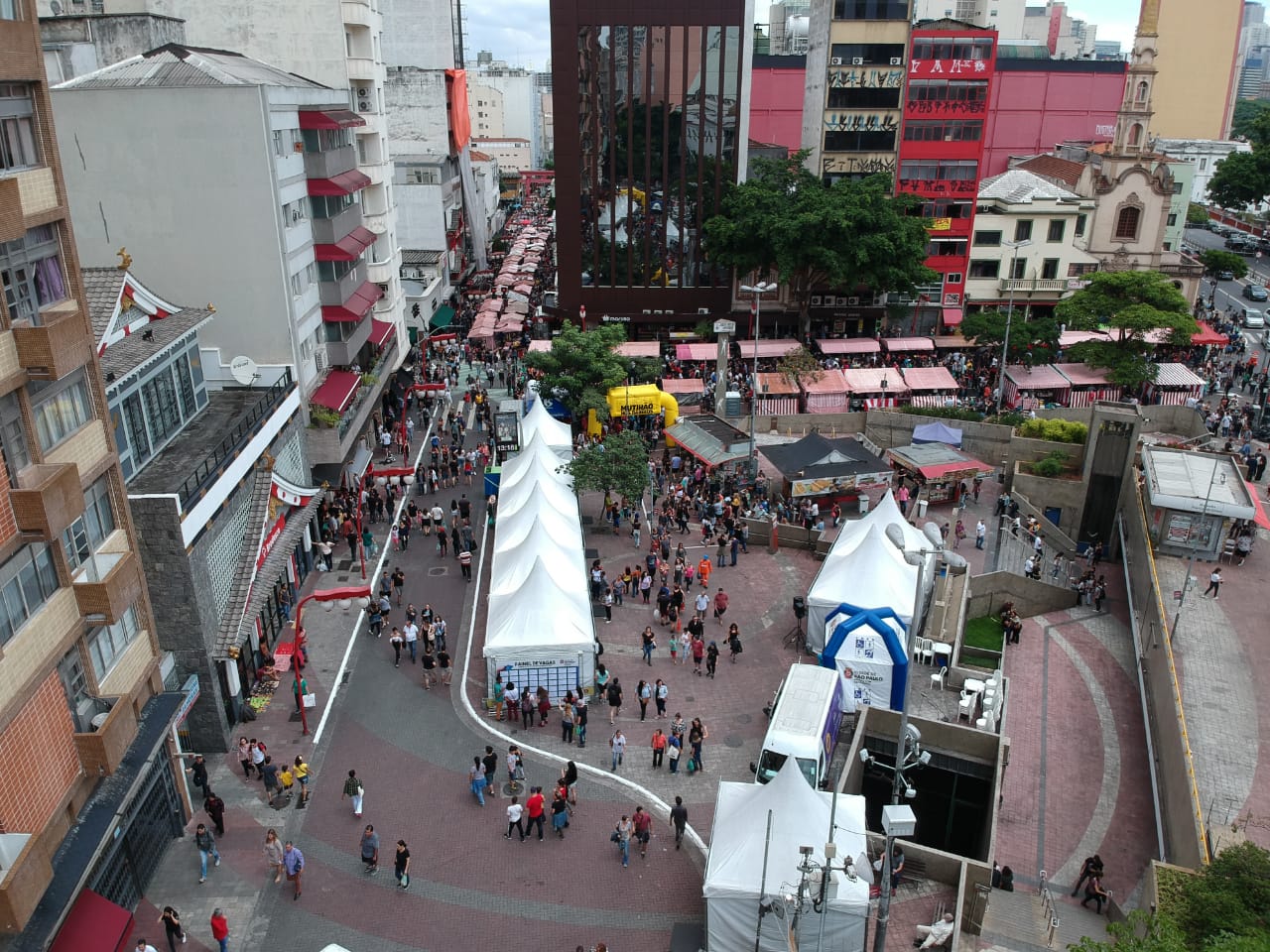 Foto área da praça da Liberdade. Observa-se tendas, pessoas e prédios.