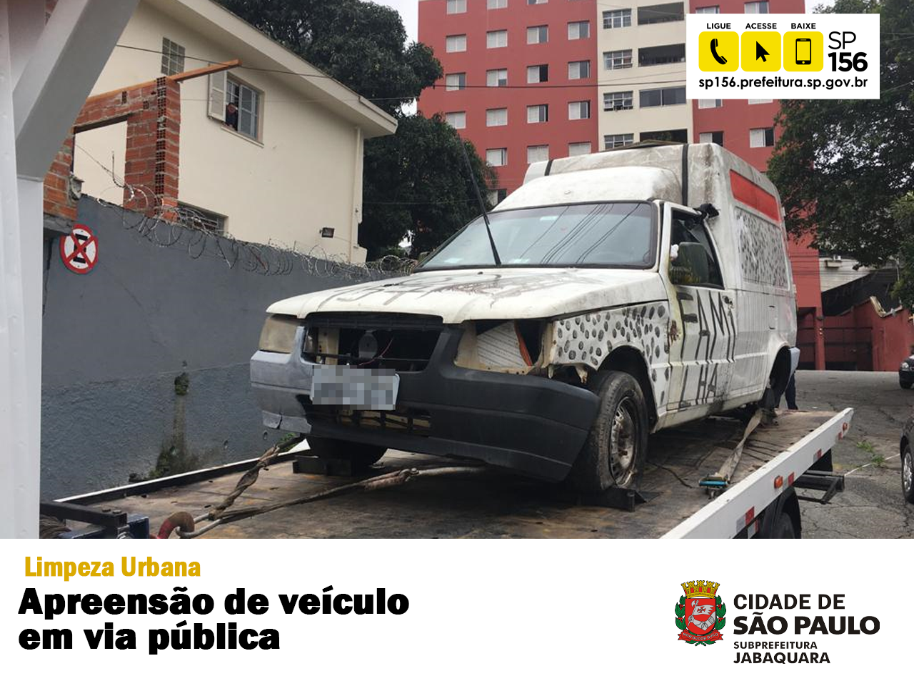 Imagem de um carro em cima do guincho, no rodapé existe uma faixa branca escrito "Limpeza Urbana - Apreensão de veículos em via pública" e mais ao canto inferior direito o logotipo da Subprefeitura Jabaquara. No canto superior direito tem o ícone com o telefone do 156.