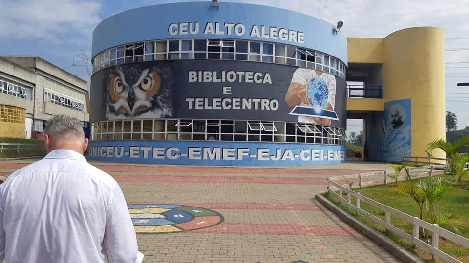 Prédio do Ceu Alto Alegre com os dizeres "Telecentro e Biblioteca". Um homem está de costas à esquerda da imagem.