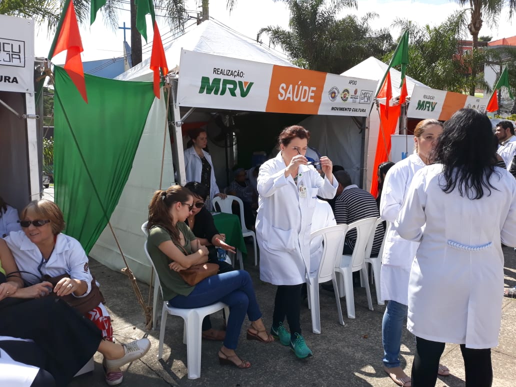 Na imagem está a tenda organizada pela Supervisão de Saúde para a campanha de vacinação, junto estão munícipes e funcionários da equipe de Saúde