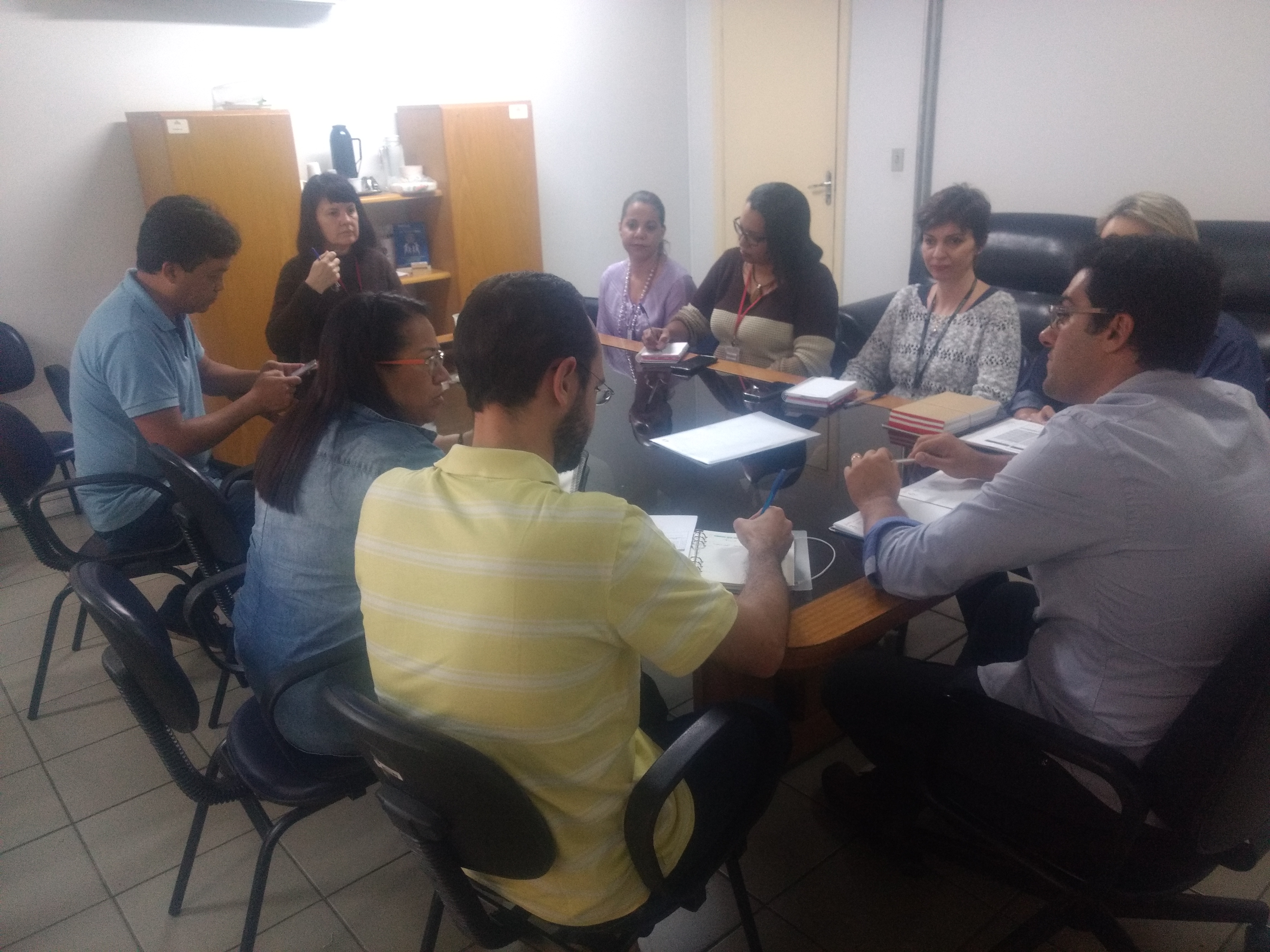 sentado na ponta da mesa de reunião, o subprefeito Roberto Bernal ouve os representantes da Saúde falarem sobre o aumento dos casos de dengue. Nove pessoas participam do encontro.  