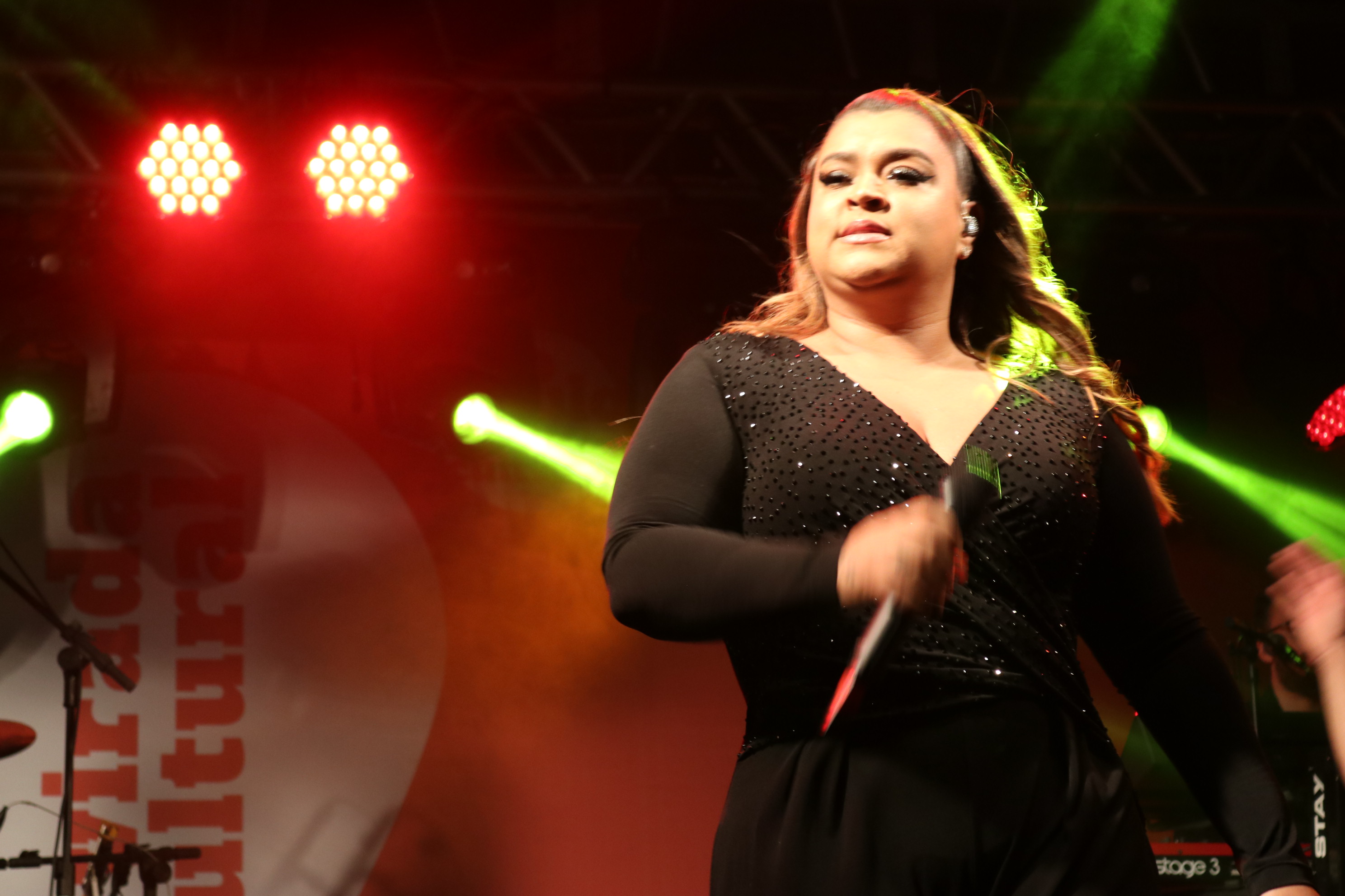 Cantora Preta Gil em destaque no palco com microfone na mão 