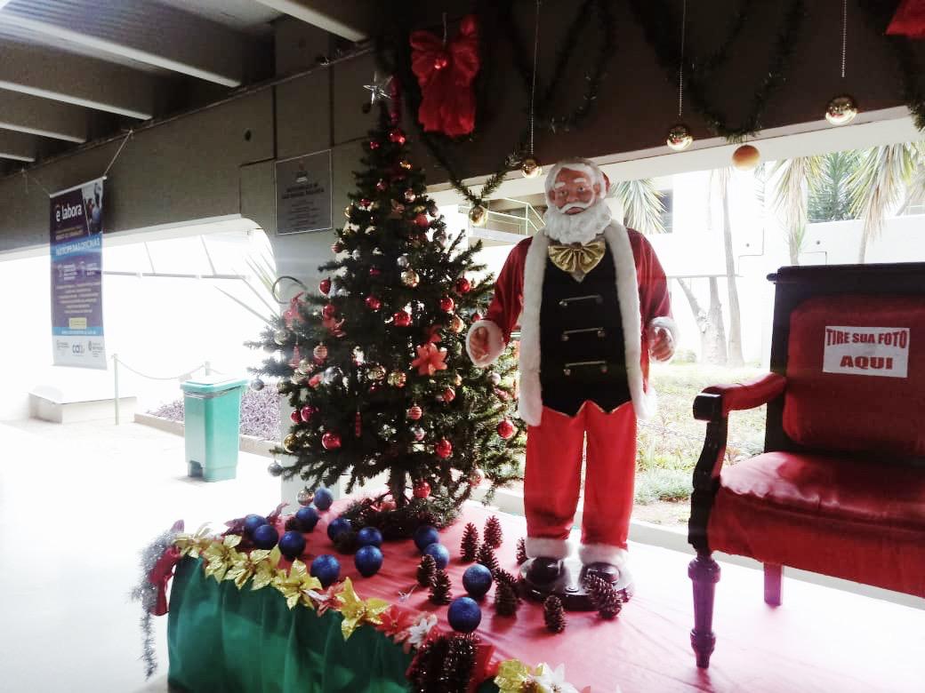 Na foto um boneco do papai noel com a cadeira ao lado com a frase "tire sua foto aqui"