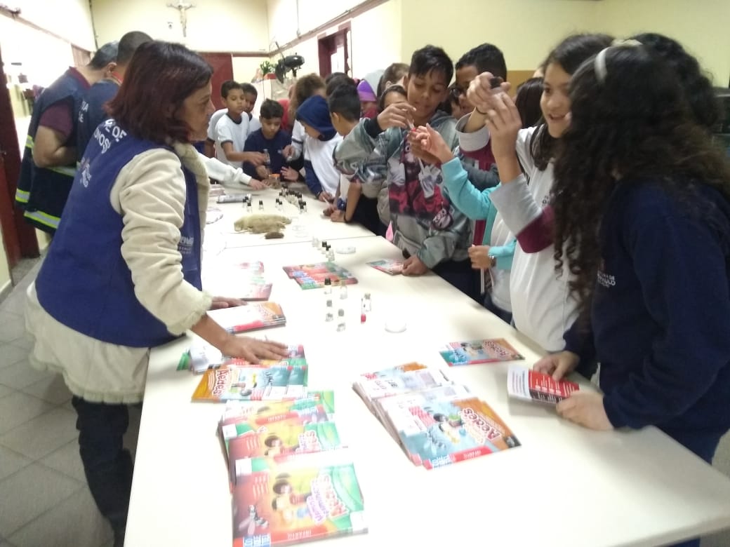 Na foto alunos observam o material informativo sobre a dengue