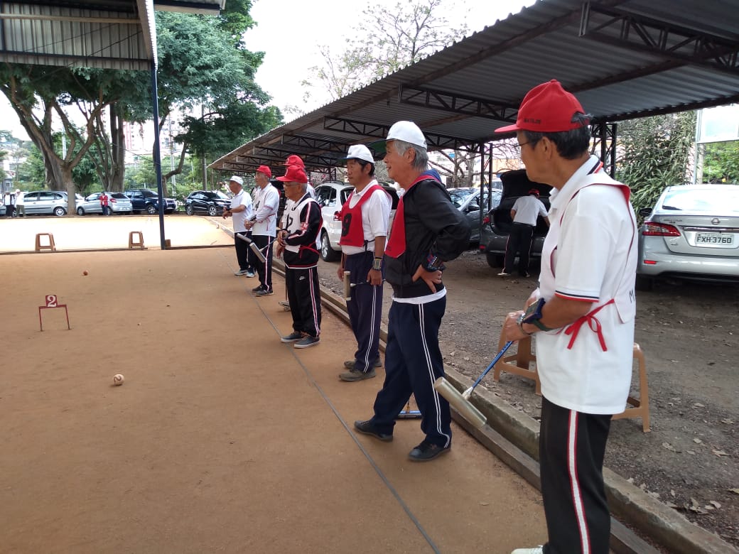 na foto os jogadores estão enfileirados observando o jogo no canto da quadra 