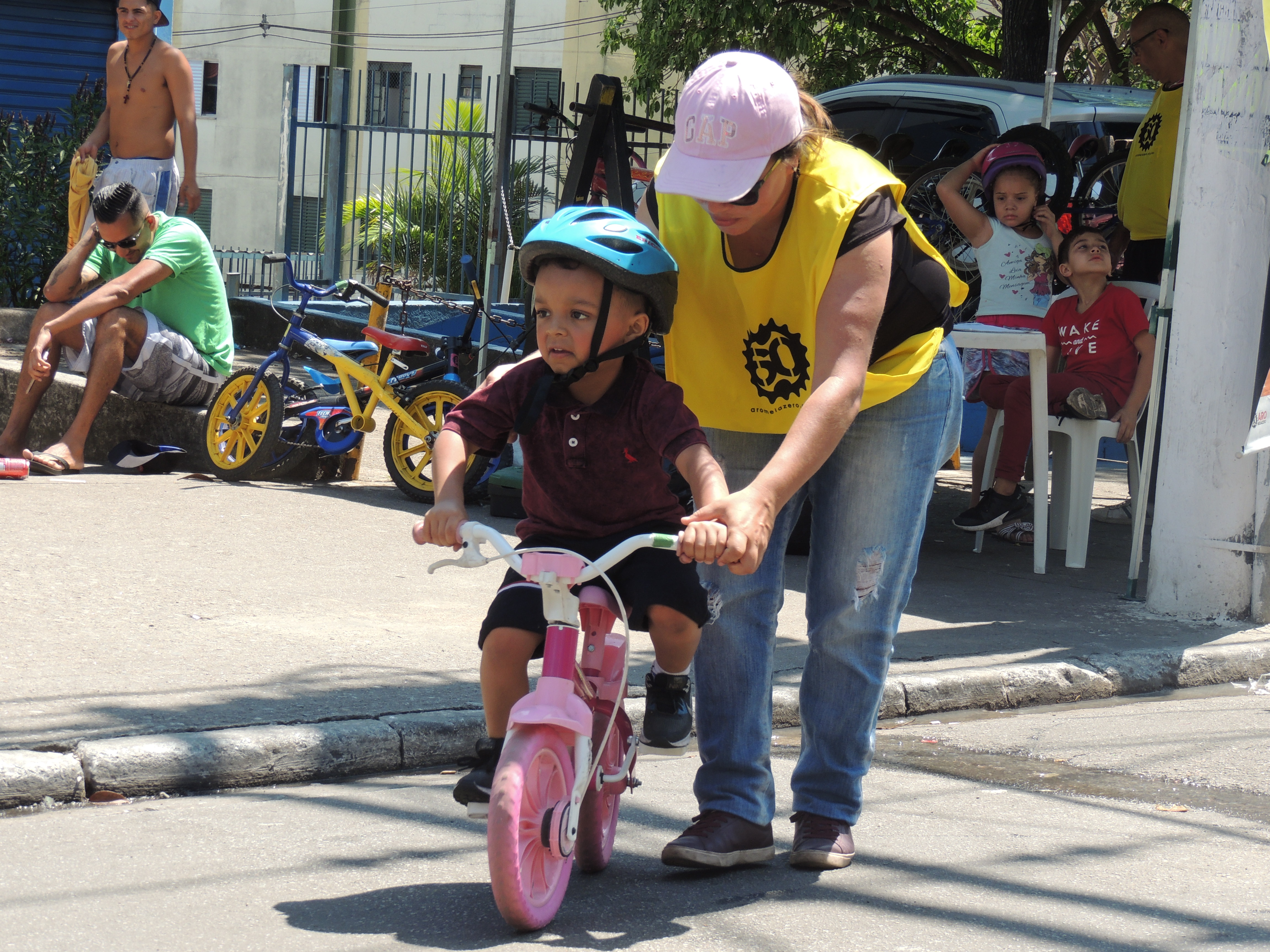 na imagem uma pessoa do bike arte, ensinando uma criança a andar de bicicleta 
