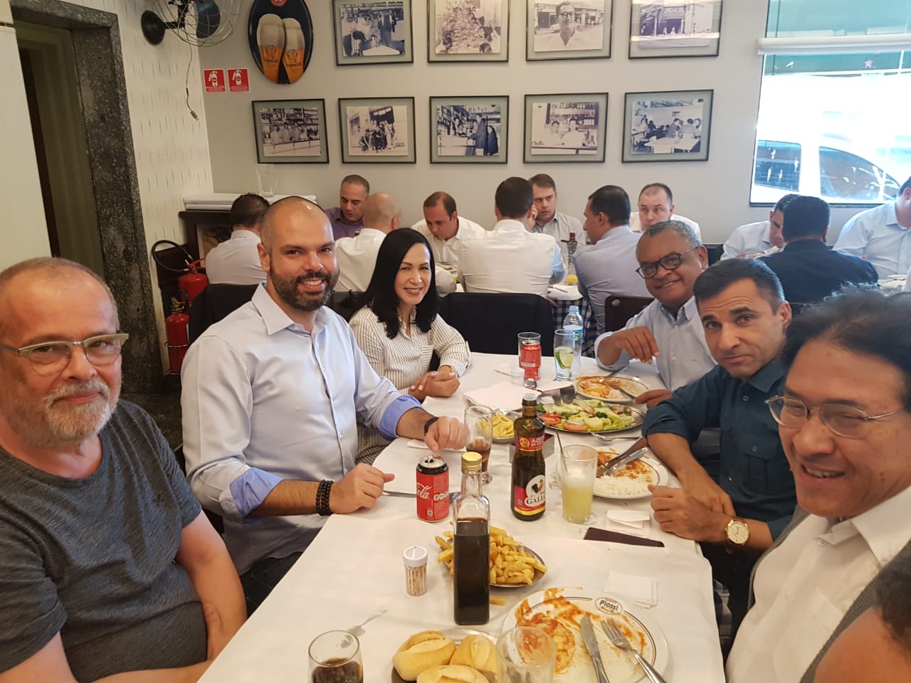 A foto mostra o Prefeito Bruno Covas, sentando ao lado de vereadores da região em um restaurante