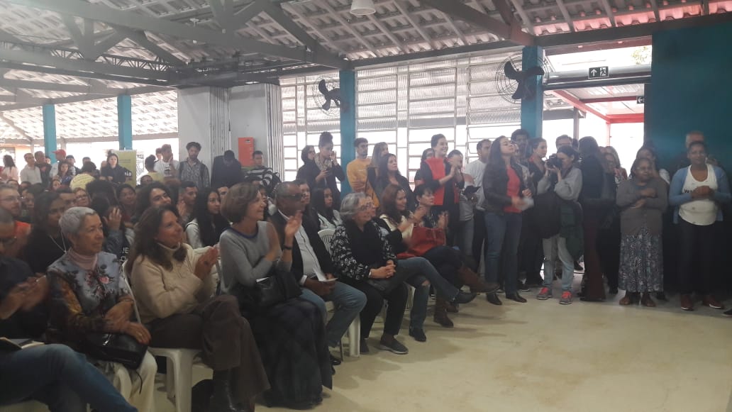 Pessoas sentadas na plateia entre elas Presidente do Conselho da Fundação Tide Setual, Maria Alice Setubal e o Subprefeito Edson Marques