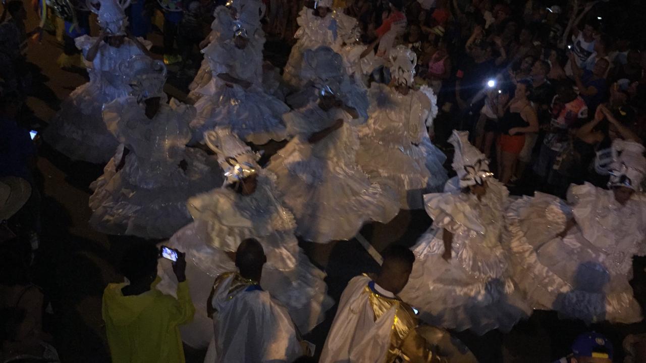 A foto em plano aberto mostra as baianas da escola de samba unidos de são miguel, vestidas de branco