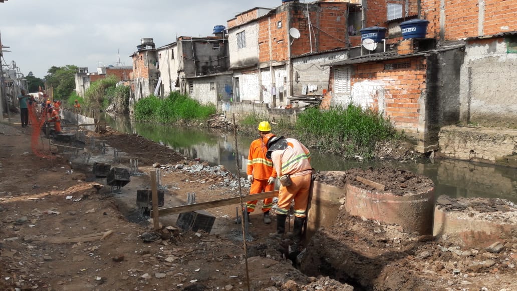Em plano aberto a foto mostra dois funcionários trabalhando em uma vala, onde será construído o Pôlder