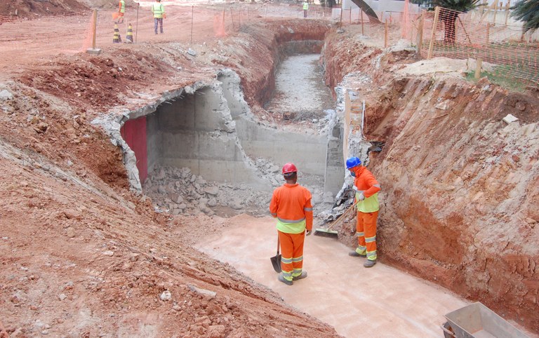 Foto colorida mostra dois trabalhadores uniformizados em meio a obras do Vale do Anhangabaú