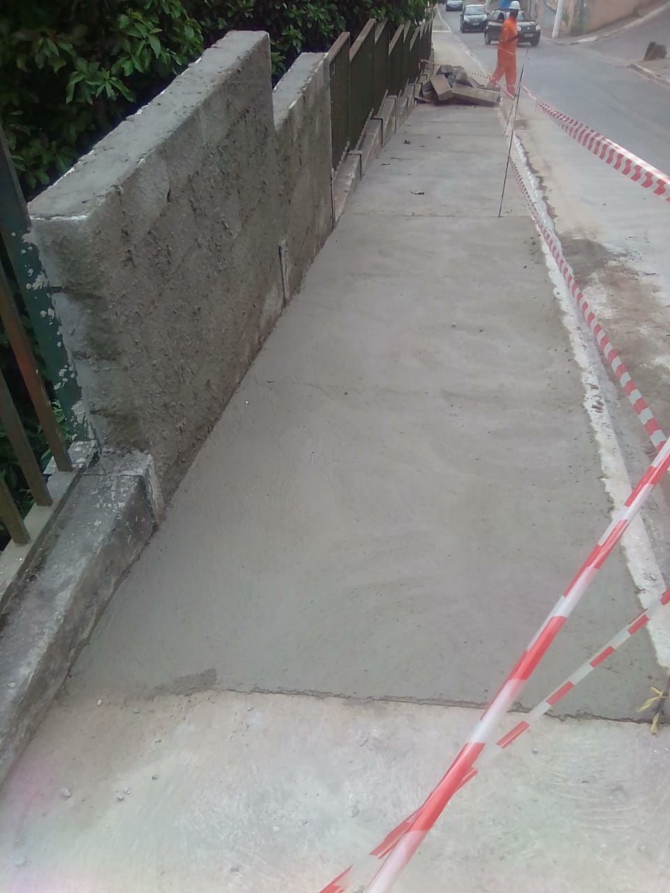 Muro com bloco de cimento foi concluído recentemente. Está chapiscado. Calçada foi refeita, está com sinal de cimento ainda para secar.