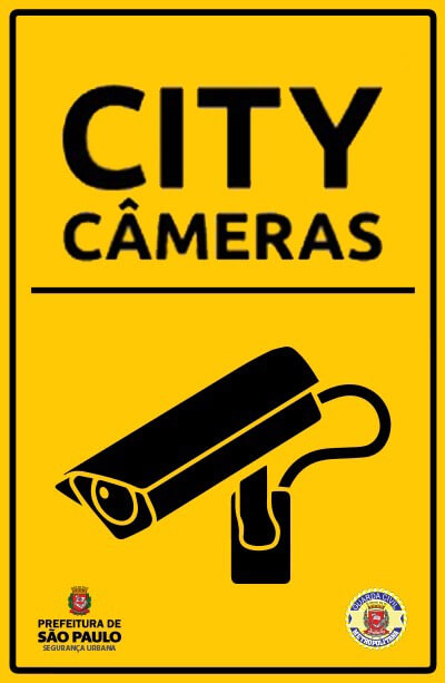 Cartaz amarelo com bordas internas de cor preta. No centro está escrito City Câmera, abaixo há um desenho de uma câmera de segurança, ambos em cor preta. O logo da Secretaria de Segurança Urbana encontra-se no canto inferior esquerdo, já o logo da Guarda Civil Metropolitana está localizado no canto inferior direito.