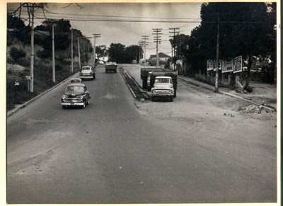 Foto preto e branco da Avenida Francisco Morato em 1959. Na avenida passam alguns caminhões e carros, as calçadas eram curtas, assim como o canteiro central. Em todas as calçadas há postes de transmissão de energia elétrica e apenas no canto direito, após a calçada, temos 4 outdoors. Existe uma grande presença de árvores no local da imagem.