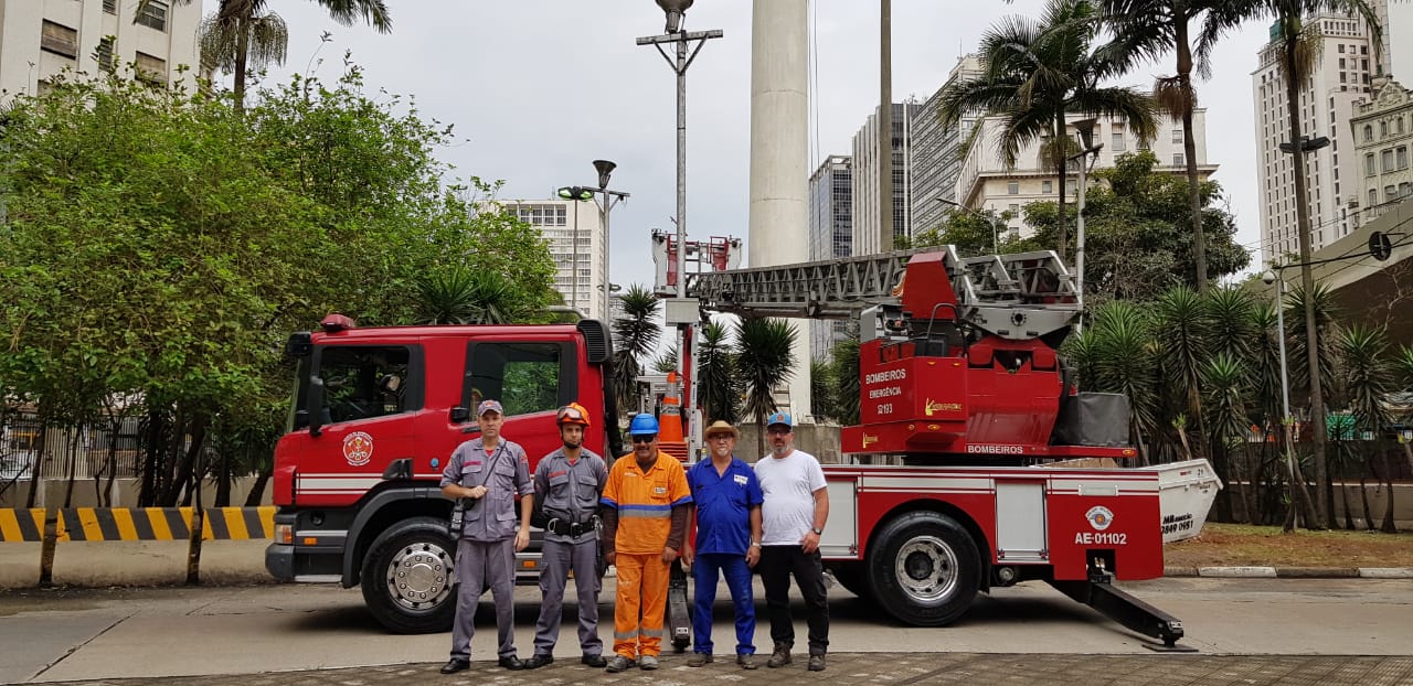 Equipe da troca da bandeira da Praça da Bandeira. Atrás, um caminhão do corpo de bombeiros