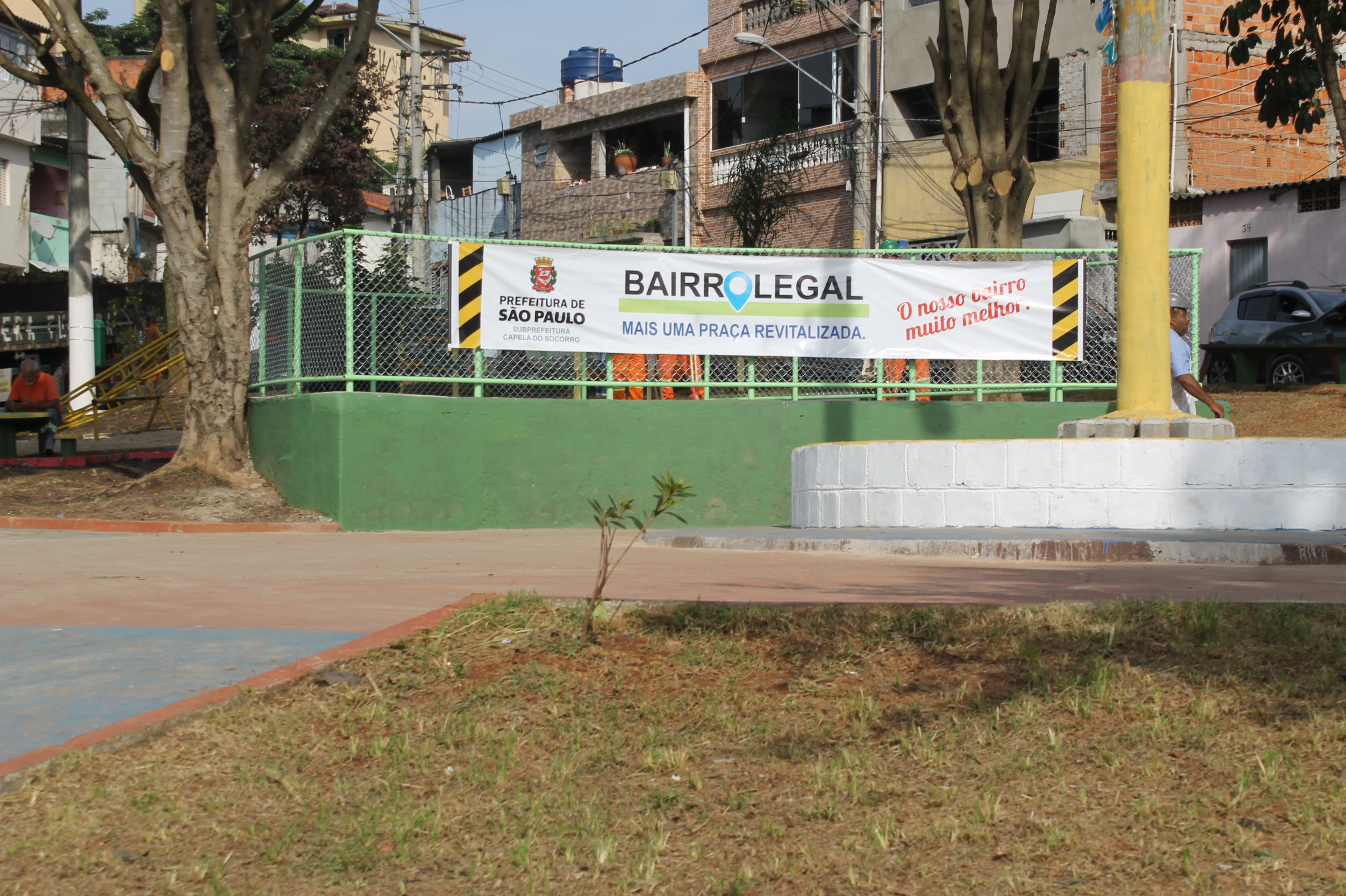 #PraCegoVer - Praça da Vila da Paz com a faixa no dia da entrega. Na faixa, se lê: Bairro Legal. Mais uma praça revitalizada. Nosso Bairro muito melhor.
