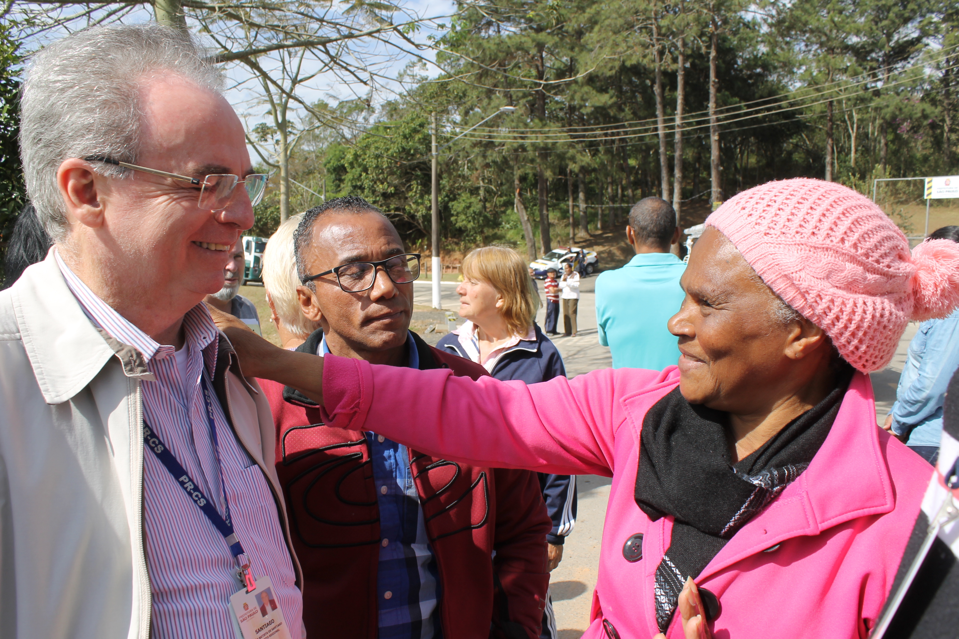 #PraCegoVer - Do lado esquerdo, o subprefeito João Batista de Santiago conversa com dona Marinalva, moradora do local. Santiago usa óculos, tem cabelos brancos e veste uma jaqueta clara. Dona Marinalva usa um casaco cor de rosa sobre echarpe cinzenta, além de uma touca de crochê também cor de rosa.