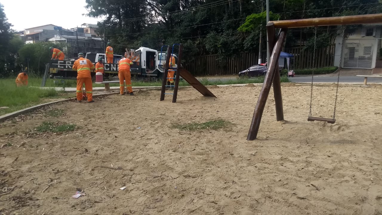 #PraCegoVer - Trabalhadores aplainam o solo e cortam a grama. Ao lado, há brinquedos para crianças.