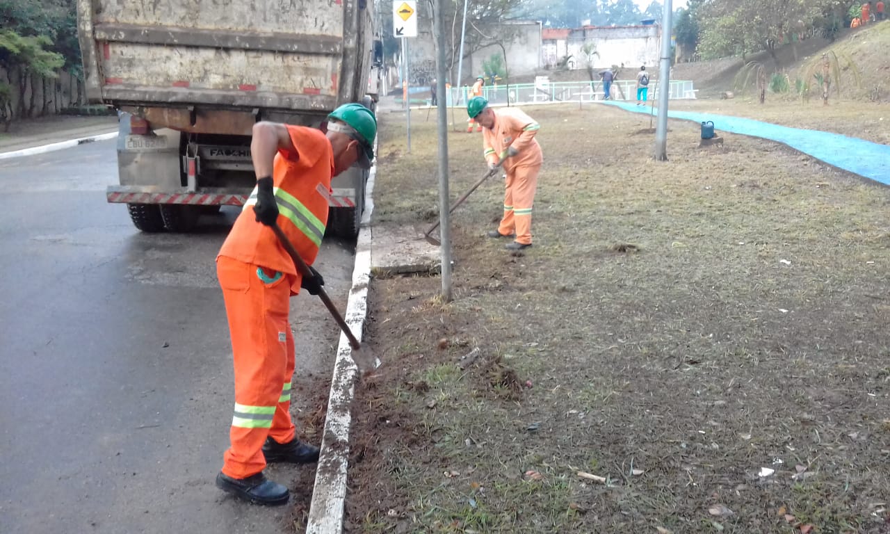 #PraCegoVer - Dois trabalhadores capinam o canteiro da avenida