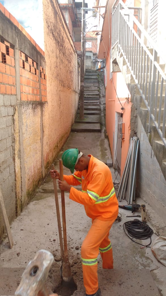 #PraCegoVer - Trabalhador da Subprefeitura cava o chão da escadaria. Ao lado, há canos para corrimão.