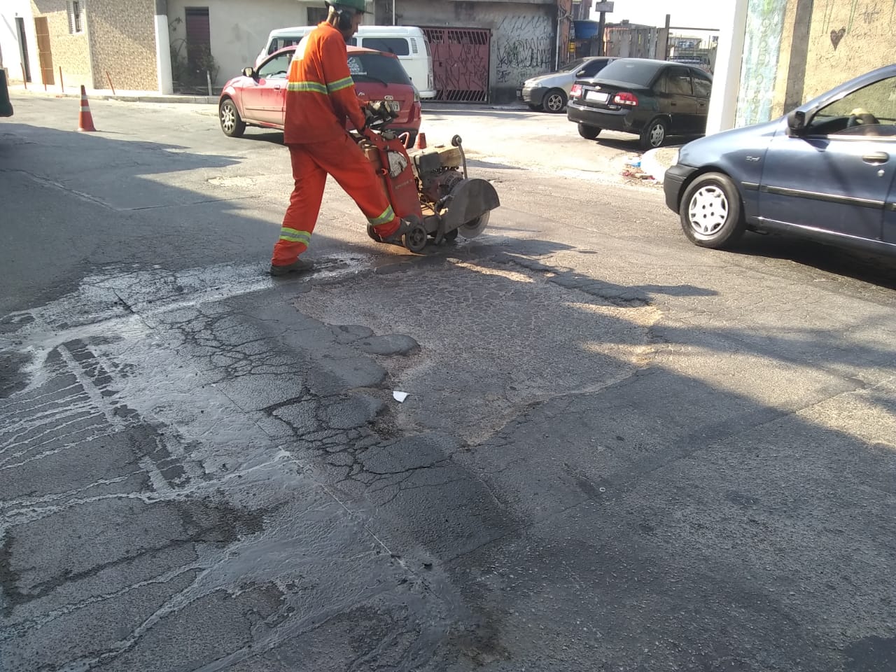 #PraCegoVer - Na primeira foto, um trabalhador da Subprefeitura faz corte do asfalto, com máquina, demarcando a área a ser tapada. Na segunda foto, o local já tapado.