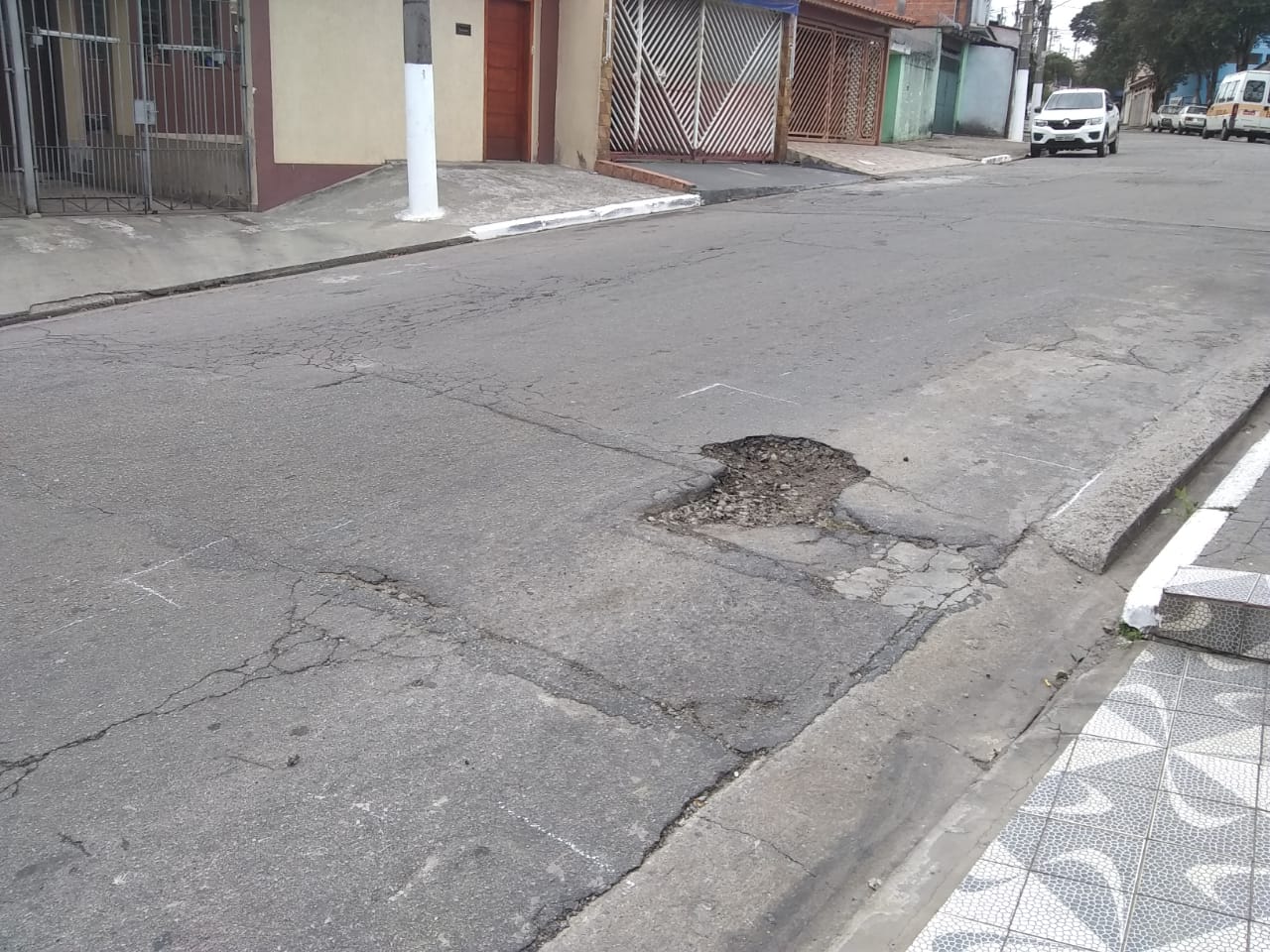 #PraCegoVer - Na primeira foto, buraco na lateral da via, perto de uma entrada de carro. Na segunda foto, o buraco já tapado.