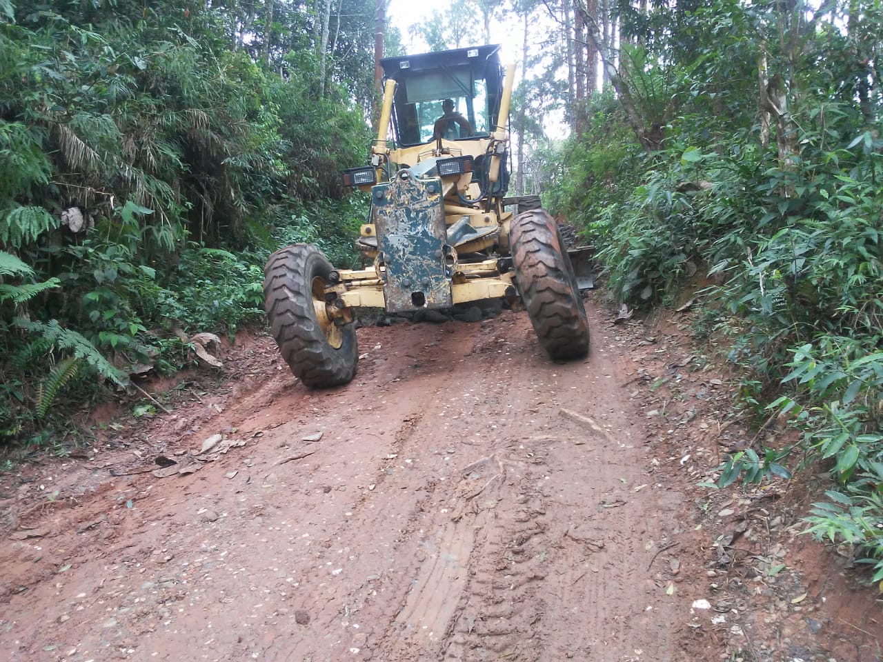 #PraCegoVer - Motoniveladora raspa a terra da via para compactar o solo e melhorar a via.