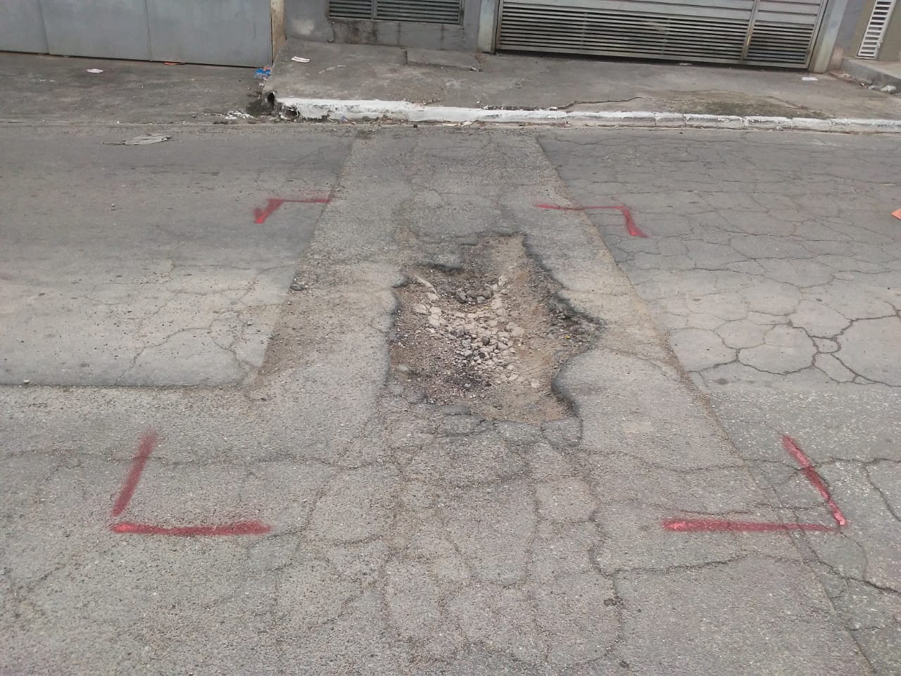#PraCegoVer - Na primeira foto, o buraco no centro da rua, com os limites demarcados. Na foto seguinte, o buraco já tapado. Ao fundo, um rolo compressor.
