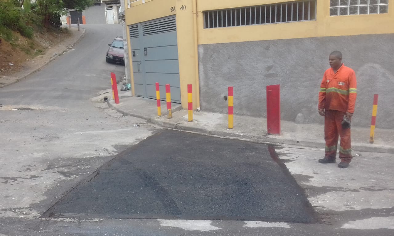 #PraCegoVer - Na primeira foto, o buraco na via, diante de estacas de segurança pintadas de amarelo e vermelho. Na segunda foto, o buraco já tapado.