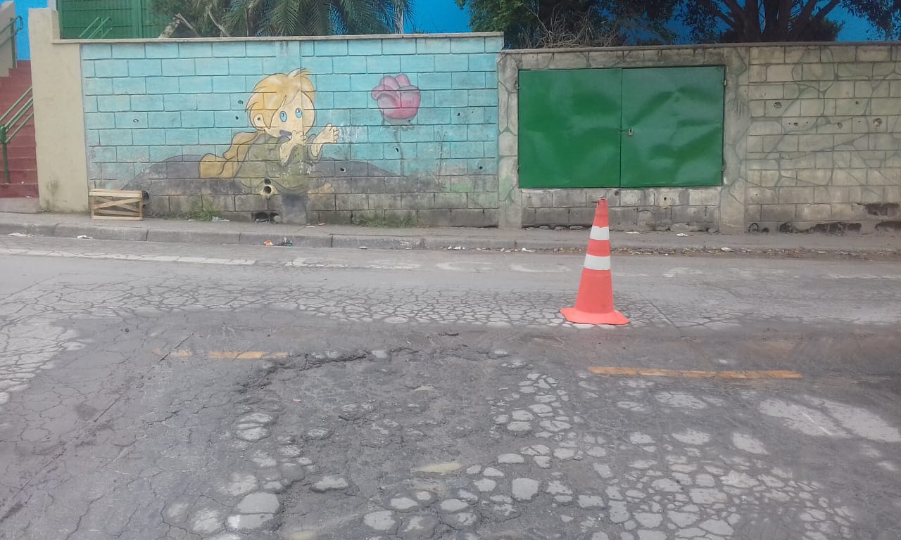 #PraCegoVer - Na primeira foto, o buraco em preparação. A via está diante de um muro com um grafitti com um menino e uma flor. Na segunda foto, o buraco já tapado.