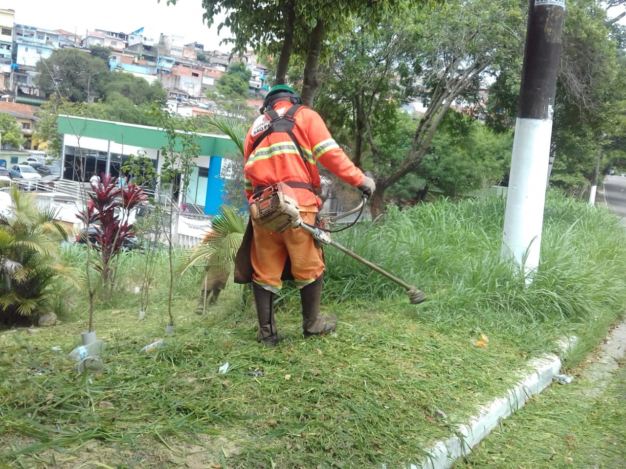 #PraCegoVer - Trabalhador da Subprefeitura corta grama e mato no passeio, perto do Pronto Socorro Maria Antonieta