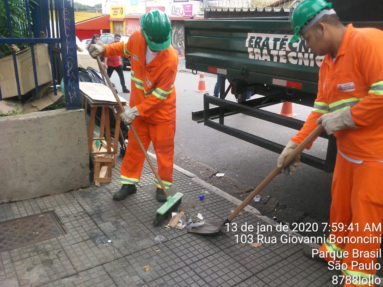 #PraCegoVer - Trabalhadores da Subprefeitura recolhem últimos restos do desfazimento, com vassoura e pá.