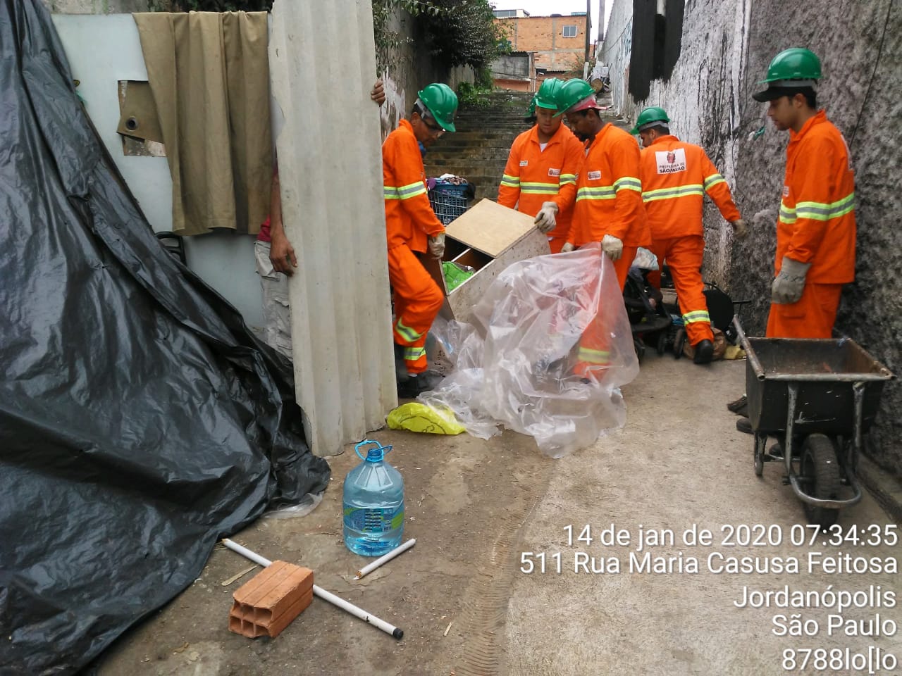 #PraCegoVer - Trabalhadores da Subprefeitura recolhem materiais em sacos de plástico para limpar o local.