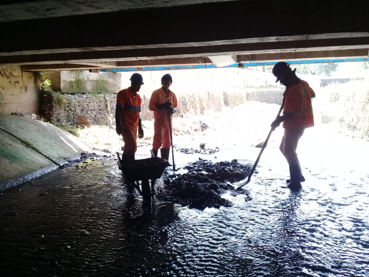 #PraCegoVer - Trabalhadores da Subprefeitura limpam detritos do córrego, sob a passagem da via superior. Na segunda foto, o córrego já limpo.