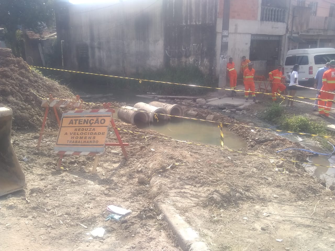 #PraCegoVer - Trabalhadores da Subprefeitura iniciam trabalho de assentamento de tubos da galeria. O local está sinalizado com placas e fitas.