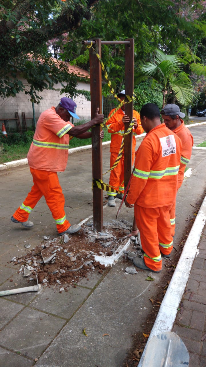 #PraCegoVer - Trabalhadores da Subprefeitura instalam uma barra de exercícios na calçada do Laguinho.