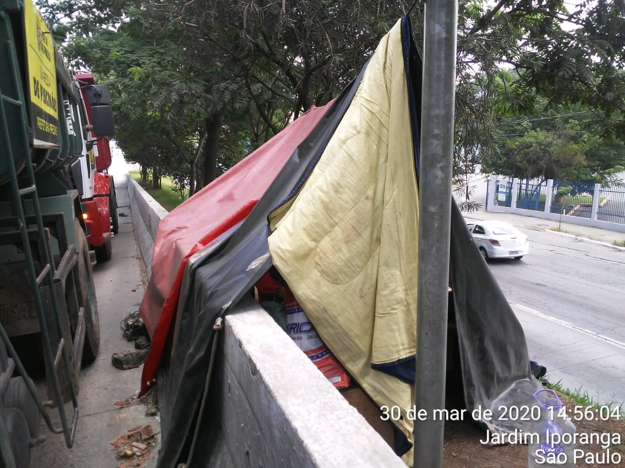 #PraCegoVer - Caminhão da empreiteira contratada ao lado de uma tenda armada por moradores de rua no canteiro central da via