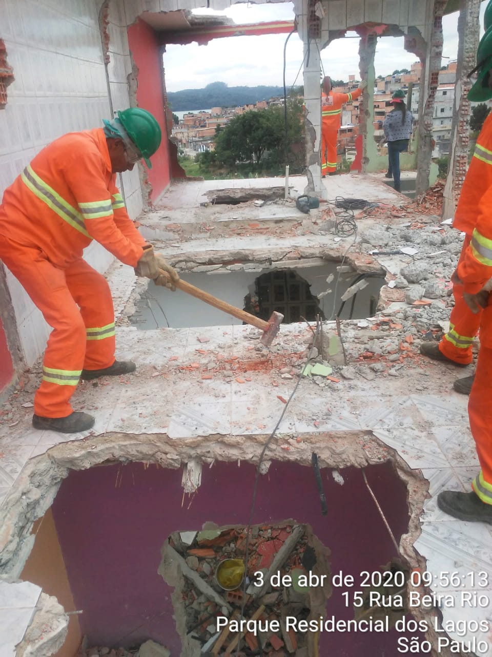 #PraCegoVer - Trabalhadores da Subprefeitura fazem demolição de prédio embargado na via.