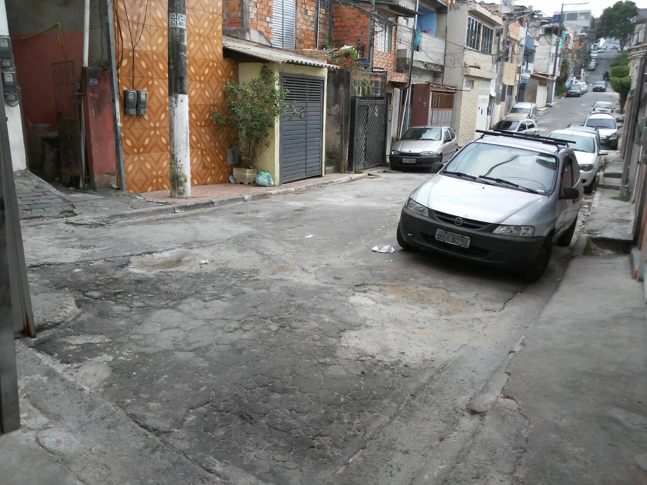  #PraCegoVer - Na primeira foto, os buracos no asfalto, perto de carros estacionados à direita e de um prédio marron à esquerda. Na foto seguinte, os buracos já tapados.